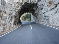 an image of the road going through a tunnel on top of mountains in italy on a clear day
