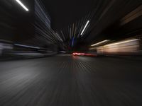 a car driving on a city street at night time, in motion with its headlights on