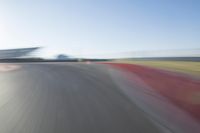 the camera is blurred from a car passing by the track and the other cars are in the background