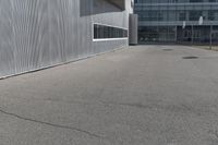 a yellow fire hydrant is on the empty pavement near a building with grey siding