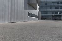 a yellow fire hydrant is on the empty pavement near a building with grey siding