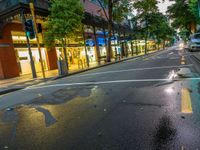 the intersection has red bricks and blue signs on the curb in front of store fronts