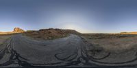 a circular view of a desert in the middle of nowhere, near an asphalt roadway