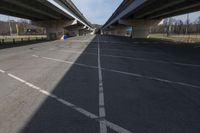 a bridge that's connecting two large road spans over a parking lot area as seen from under