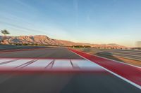 a photo of a dirt race track with sun setting in the distance of the track