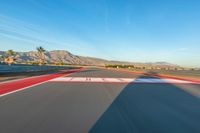 a photo of a dirt race track with sun setting in the distance of the track