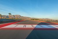 a photo of a dirt race track with sun setting in the distance of the track