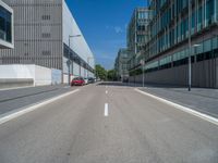 an empty city street next to tall buildings and street lamps on a sunny day in the summer