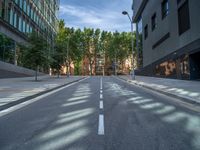 a narrow road in between buildings on either side of street are tall trees and street lights