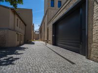 two windows in the side of a brick building, with a black garage door and brown door