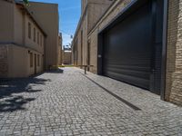 two windows in the side of a brick building, with a black garage door and brown door