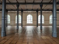 empty, large room with wood parquet floor and many windows and arches with wood parquet floors