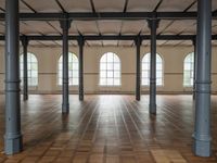 empty, large room with wood parquet floor and many windows and arches with wood parquet floors