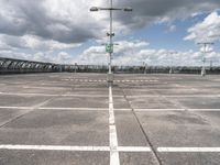 empty parking lot full of traffic signs with a cloudy sky above it and the streetlights