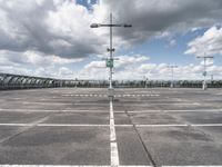 empty parking lot full of traffic signs with a cloudy sky above it and the streetlights