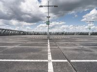 empty parking lot full of traffic signs with a cloudy sky above it and the streetlights