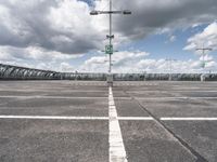 empty parking lot full of traffic signs with a cloudy sky above it and the streetlights