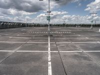 empty parking lot full of traffic signs with a cloudy sky above it and the streetlights