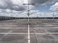 empty parking lot full of traffic signs with a cloudy sky above it and the streetlights