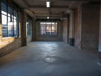 a large open floor with light shining on it's surface and brick walls, exposed ceilings and windows