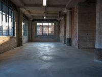 a large open floor with light shining on it's surface and brick walls, exposed ceilings and windows