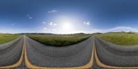 the road looks very straight as it crosses the grass land in front of the sun