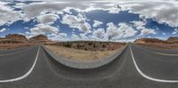 two lane wide angle view on an empty road in the desert against cloudy sky and rocks