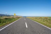 a road leading to the ocean with a stop sign at either end of it and grass growing on the sides