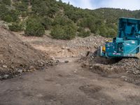 two yellow bulldozers work on sand and gravel in a mountain valley while another one looks at it