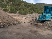 two yellow bulldozers work on sand and gravel in a mountain valley while another one looks at it