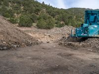 two yellow bulldozers work on sand and gravel in a mountain valley while another one looks at it