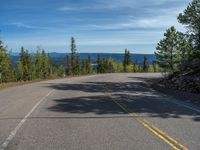 the mountains are visible in the distance from this wide, empty road, overlooking a wide landscape and forest