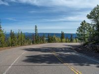 the mountains are visible in the distance from this wide, empty road, overlooking a wide landscape and forest