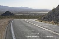 a motorcycle riding down a winding highway between hills and dry grass on a sunny day