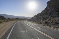 a motorcycle riding down a winding highway between hills and dry grass on a sunny day