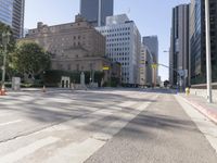 the empty road has an orange traffic cone along it near some tall buildings in downtown san diego