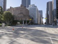 the empty road has an orange traffic cone along it near some tall buildings in downtown san diego