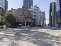 the empty road has an orange traffic cone along it near some tall buildings in downtown san diego