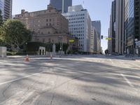 the empty road has an orange traffic cone along it near some tall buildings in downtown san diego