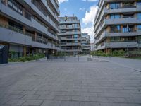 an empty parking area in front of large buildings with lots of windows and balconies