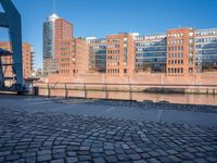 a black skateboard is standing on the road next to a brick path and some buildings