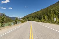 a deserted highway in the mountains with pine trees and mountains in the background, taken from the front seat