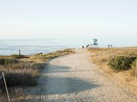 a view of the ocean from a path that leads to the beach and has a life guard stand