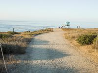 a view of the ocean from a path that leads to the beach and has a life guard stand