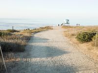 a view of the ocean from a path that leads to the beach and has a life guard stand