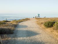 a view of the ocean from a path that leads to the beach and has a life guard stand