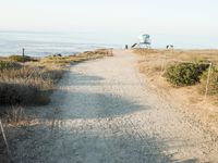 a view of the ocean from a path that leads to the beach and has a life guard stand