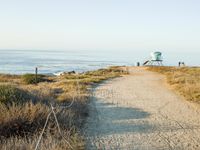 a view of the ocean from a path that leads to the beach and has a life guard stand