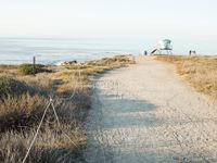 a view of the ocean from a path that leads to the beach and has a life guard stand