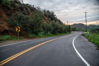 a road with a yellow sign on it in the daytime or the day time at sunset